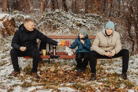 Snowy Park Serenity: Dad and Sons Share Treats and Smiles in a Winter Wonderland.