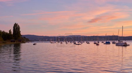 Bodensee Lake Sunrise Panorama. Morning Sunlight Over Tranquil Waters. Witness the mesmerizing dawn over Germanys Bodensee Lake, captured from a boat dock. Embrace the tranquil beauty of the early