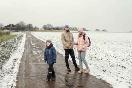 Bienaventuranza de la familia de invierno: Madre y dos hijos disfrutando de un paseo nevado por la campiña