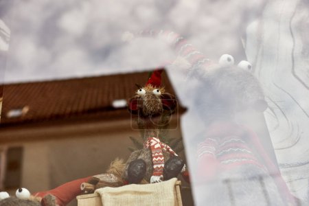 Souris fantaisiste du Nouvel An dans le chapeau et l'écharpe se tient derrière l'affichage du magasin. Capturez le charme de la période des Fêtes avec cette charmante image mettant en vedette une souris ou un rat jouet portant un Nouvel An comique