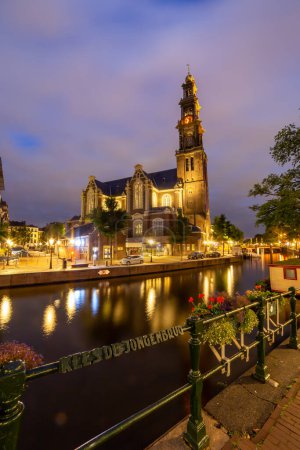 Téléchargez les photos : Evening view on onto westkerk in amsterdam from kees de jongenbrug lanterns reflecting in the water - en image libre de droit