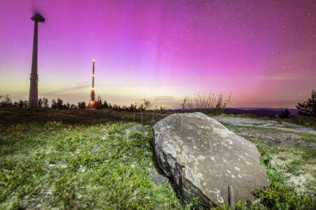 stone in front of pink colorful northern lights sky above hornisgride in Baden-wuerttemberg, germany