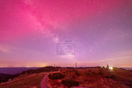 milky way above hornisgride in Baden-wuerttemberg, germany with slight red northern lights on the sky from bismarckturm