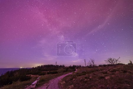 milky way above hornisgride in Baden-wuerttemberg, germany with slight red northern lights on the sky path leading to milky way