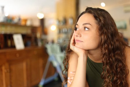 Foto de Mujer distraída y pensativa mirando hacia otro lado en un restaurante - Imagen libre de derechos