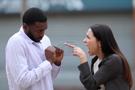 Photo for Furious woman scolding to a black man in the street - Royalty Free Image