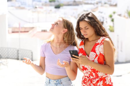 Téléchargez les photos : Touristes perdus vérifier téléphone intelligent en vacances dans une ville debout dans la rue - en image libre de droit
