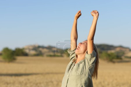 Téléchargez les photos : Jeune levant les bras dans un champ de blé doré au coucher du soleil - en image libre de droit