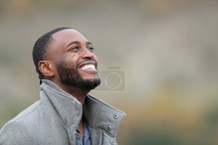 Téléchargez les photos : Heureux homme noir riant levant les yeux en hiver à l'extérieur - en image libre de droit