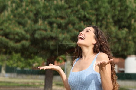 Téléchargez les photos : Femme excitée sous la pluie soudaine levant les yeux - en image libre de droit