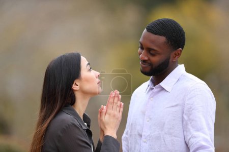 Photo for Woman begging forgive to a black man in a park - Royalty Free Image