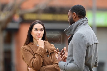 Photo for Suspicious woman listening a man talking in the street in winter - Royalty Free Image