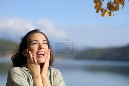 Téléchargez les photos : Surprised happy woman looking above in a lake on holiday with copy space - en image libre de droit