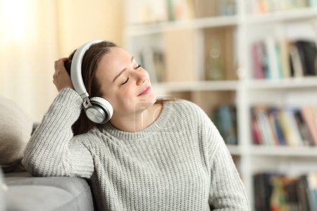 Foto de Happy teen wearing headphones listening to music at home - Imagen libre de derechos