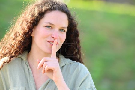 Photo for Happy woman asking for silence outside with finger on lips - Royalty Free Image