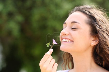 Téléchargez les photos : Happy candid woman smelling little flower in a park - en image libre de droit