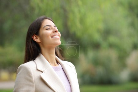 Téléchargez les photos : Happy woman in winter breaths fresh air in a park - en image libre de droit