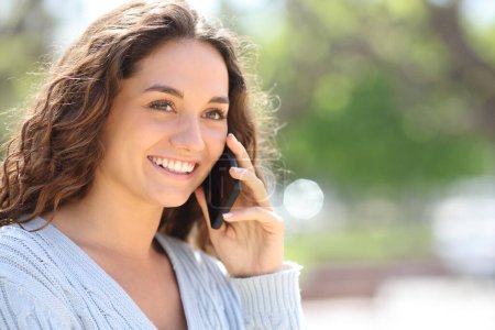 Téléchargez les photos : Happy woman talks on phone walking outside - en image libre de droit