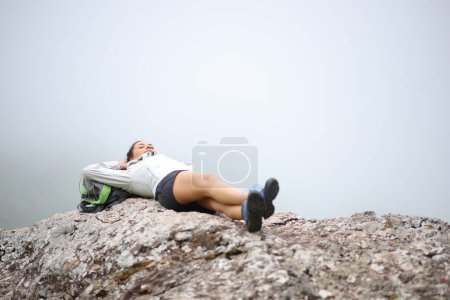 Téléchargez les photos : Hiker resting lying on a rock in the mountain a foggy day - en image libre de droit