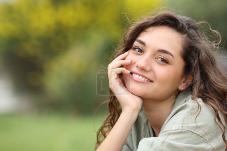 Foto de Portrait of a beautiful woman smiling at you in a park - Imagen libre de derechos