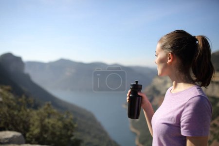 Téléchargez les photos : Sportswoman holding drink watching landscape in nature - en image libre de droit