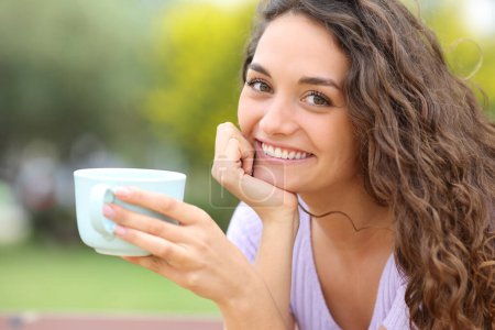 Téléchargez les photos : Happy woman holding coffee cup posing in a park - en image libre de droit