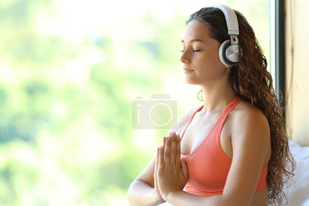 Foto de Happy woman meditating with headphone at home - Imagen libre de derechos