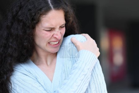Téléchargez les photos : Femme souffrant de douleurs à l'épaule se plaignant dans la rue - en image libre de droit
