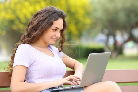 Téléchargez les photos : Woman writing on laptop sitting on a bench - en image libre de droit