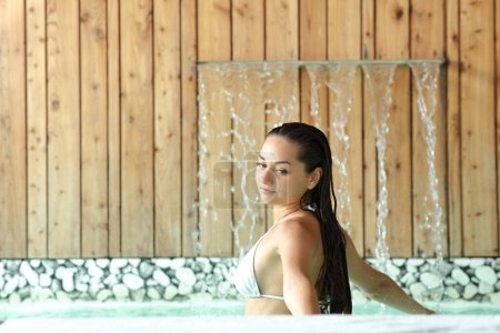 Téléchargez les photos : Femme dans une piscine spa se baignant à côté du jet d'eau - en image libre de droit