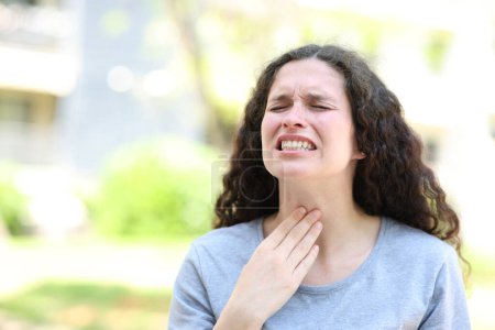 Foto de Mujer sufriendo dolor de garganta quejándose en la calle - Imagen libre de derechos