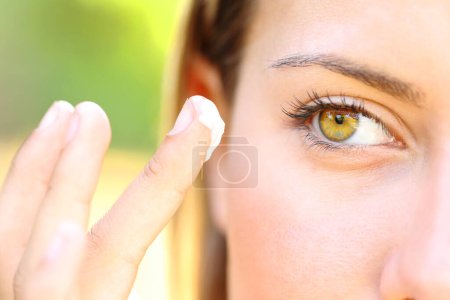 Photo for Close up of a woman with beauty eyes applying moisturizer - Royalty Free Image