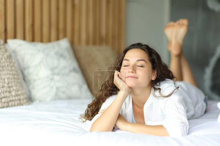 Téléchargez les photos : Joyeux belle femme couchée sur le lit relaxant - en image libre de droit