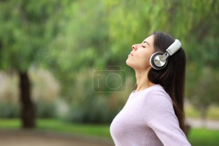 Téléchargez les photos : Profil d'une femme respirant écoutant un audioguide dans un parc - en image libre de droit