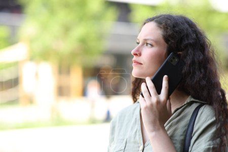 Photo for Woman talking on phone walking in the street - Royalty Free Image