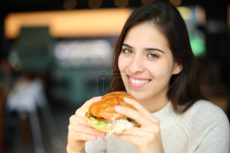 Foto de Mujer feliz lista para comer burguesa en un restaurante mirando a la cámara - Imagen libre de derechos