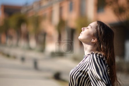 Photo for Profile of a woman breathing fresh air a sunny day in a residential area - Royalty Free Image