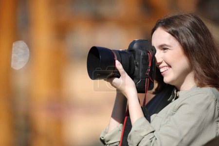 Photo for Side view portrait of a happy photographer taking photos outdoor - Royalty Free Image