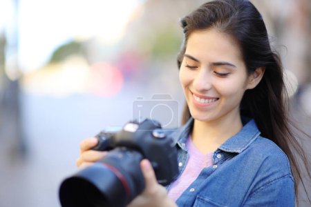 Photo for Happy photographer checking photos on camera outdoor in the street - Royalty Free Image