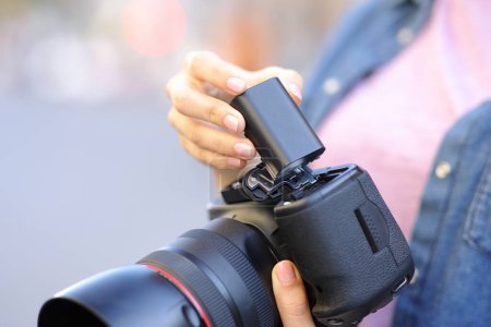 Téléchargez les photos : Gros plan portrait d'un photographe changeant de batterie à l'appareil photo - en image libre de droit