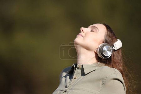 Téléchargez les photos : Femme méditant à l'extérieur écoutant audioguide avec casque - en image libre de droit
