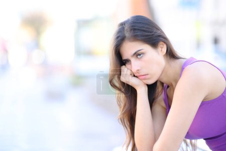 Téléchargez les photos : Femme ennuyée attendant assis dans la rue - en image libre de droit