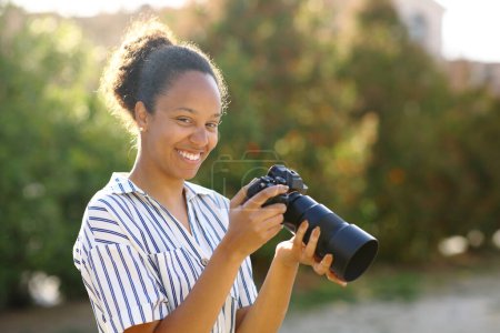 Téléchargez les photos : Joyeux photographe noir posant en regardant la caméra dans un parc - en image libre de droit