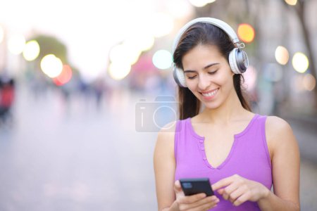 Photo for Happy woman wearing headphone in the street listening to music on phone - Royalty Free Image