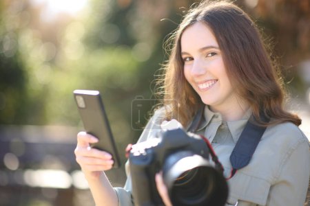 Photo for Happy photographer pairing cell phone with dslr professional camera looking at you - Royalty Free Image