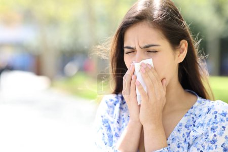 Ill woman blowing or coughing on tissue in the street