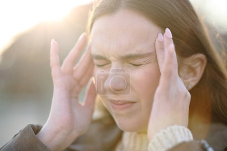 Foto de Primer plano de una mujer que sufre dolor de cabeza al aire libre y se queja - Imagen libre de derechos