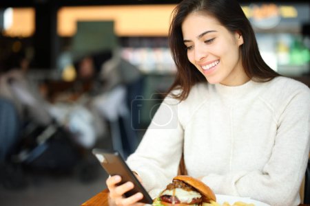 Téléchargez les photos : Client vérifiant téléphone intelligent assis dans un restaurant - en image libre de droit