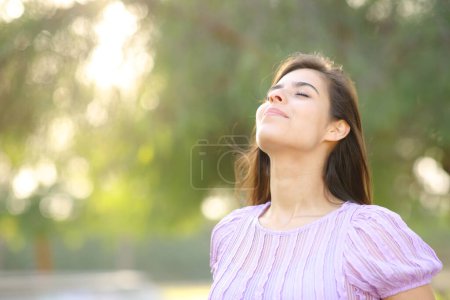 Foto de Mujer satisfecha respirando aire fresco en un parque parada sola - Imagen libre de derechos