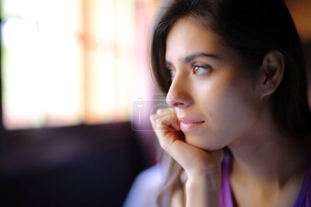 Photo for Beautiful woman relaxing looking through a window in a house interior - Royalty Free Image